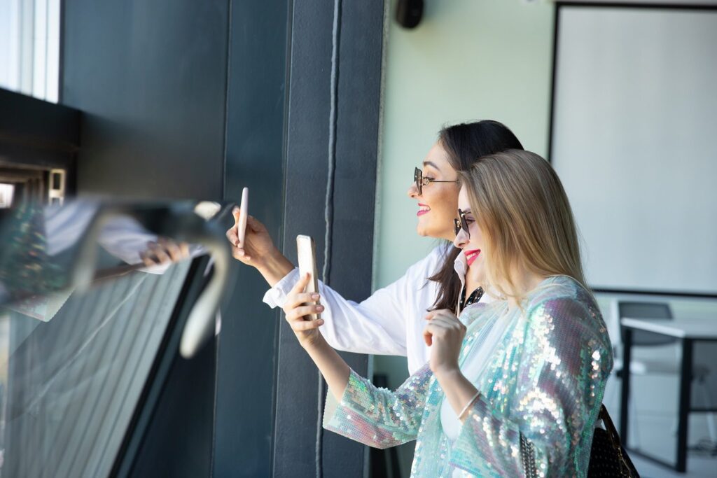 Twee vrouwen glimlachen voor hun telefoons